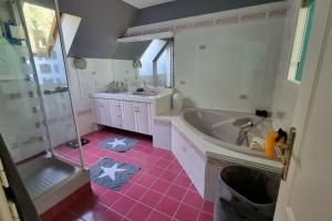 ein Badezimmer mit Badewanne und rosafarbenem Fliesenboden in der Unterkunft Calme et vue magnifique aux portes de Paris in Vaux-sur-Seine