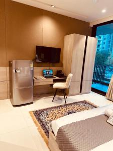 a bedroom with a refrigerator and a desk with a computer at The Lodgers Luxury Hotel Near Golf Course Road Gurgaon in Gurgaon