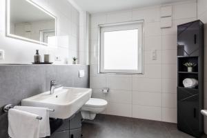 a white bathroom with a sink and a toilet at Luxuriöse Wohnung I WiFi I Jacuzzi I BBQ I Aufzug in Rheda-Wiedenbrück