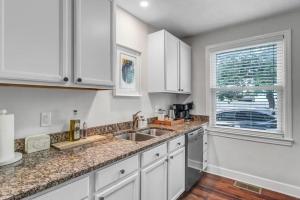 a kitchen with white cabinets and a sink and a window at Modern 2 BR Condo - 2 block from San Marco in Jacksonville