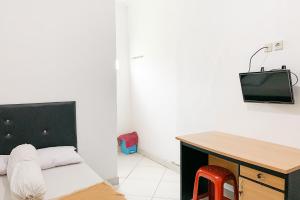 a room with a bed and a desk with a tv at Penginapan Losmen Ayu Pamanukan RedPartner in Pamanukan-hilir