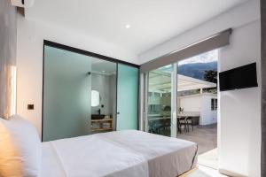 a bedroom with a large white bed and a balcony at Cyan Viewpoint House near Lake Kourna in Dhimitroulianá