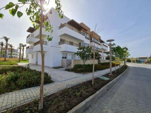 a white building with trees in front of a street at Almaza Bay Beachtown Ground Chalet in Marsa Matruh