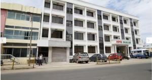 a large white building with cars parked in front of it at HOTEL BHARANI in Kanyakumari