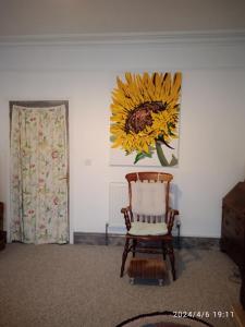 um quarto com uma cadeira e uma pintura de um girassol em Captivating 2-Bed Hideaway Apartment in Gloucester em Gloucester