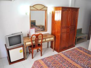 um quarto com uma secretária, uma televisão e uma cómoda em Highfive Guest House em Pattaya Central