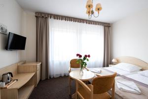 a hotel room with a bed and a table with flowers at Rewita Międzyzdroje Neptun in Międzyzdroje