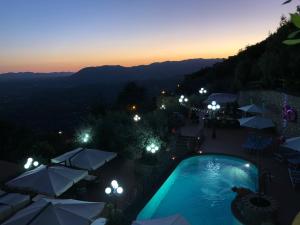 a view of a swimming pool with umbrellas at night at Belsito in Serrone