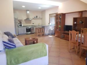 a living room with a couch and a kitchen at VibesMuxía - Casa Rural Escola in Muxia