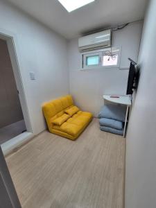a small room with a yellow couch and a table at Ribini house in Seoul