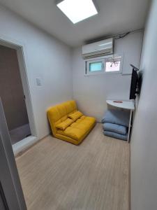 Cette petite chambre dispose d'une chaise jaune et d'un lavabo. dans l'établissement Ribini house, à Séoul