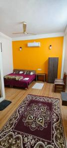 een kamer met een tapijt op de vloer en een gele muur bij Krishnashry Home in Ujjain