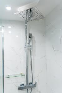a shower in a bathroom with white marble walls at Le studio du voyageur in Saint-Denis