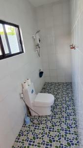 a bathroom with a toilet and a tile floor at Babas Guesthouse in Moalboal