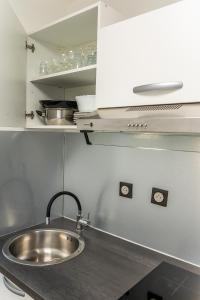 a kitchen with a stainless steel sink and cabinets at Le studio du voyageur in Saint-Denis