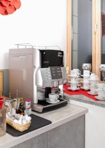 a coffee maker on a counter with cups and dishes at Algiro Hotel in Kaunas