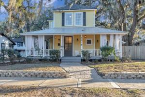 a yellow house with a porch and a fence at Farmhouse chic in San Marco - 5 min to downtown in Jacksonville