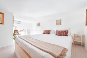 a white bedroom with a large white bed with two pillows at Palazzo Sassi in Meta