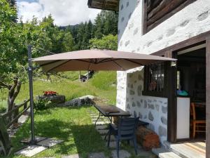 a table and chairs under an umbrella next to a building at Baita - Chalet tra Pinzolo e Madonna di Campiglio in Madonna di Campiglio