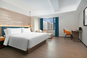 a bedroom with a large white bed and a desk at Yizhi Hotel Changgang Metro Station - Free Shuttle Bus during Canton Fair in Guangzhou