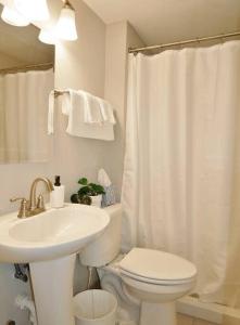 a white bathroom with a toilet and a sink at Slow Pace Beach Living - Pool - Steps from Beach in Jacksonville Beach