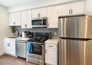 a kitchen with white cabinets and a stainless steel refrigerator at Fun Cozy 1 Br King Apts - 1 25 Mile Walk to TIAA Bnk Fld in Jacksonville