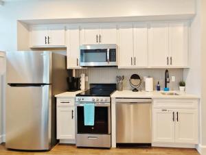 uma cozinha com armários brancos e um frigorífico de aço inoxidável em Fun Cozy Apts - 1 25 Mile Walk to TIAA Bnk Fld em Jacksonville