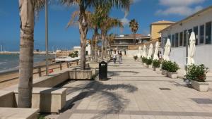 a sidewalk next to a beach with palm trees at Genova La casa di Saretta in Marina di Ragusa