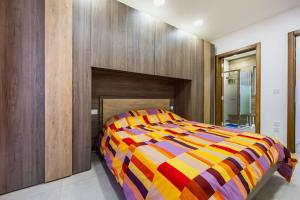 ein farbenfrohes Bett in einem Zimmer mit einer Holzwand in der Unterkunft Marsaskala 2 Bedroom Apartment in Marsaskala