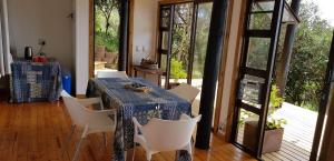 a dining room with a table and white chairs at Pequena Casa Holiday Home Malongane in Ponta Malongane