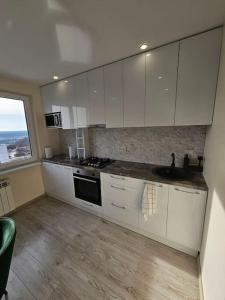 a kitchen with white cabinets and a sink and a window at Gražus ir ramus butas jonavoje in Jonava