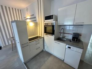 - une cuisine avec des placards blancs et un évier dans l'établissement FeWo Blankenese im Haus Lühegarten, à Grünendeich