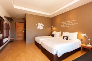 a hotel room with two beds and a tv at Blu Monkey Brown House Udonthani in Udon Thani