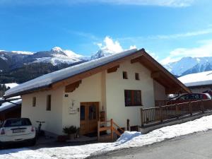 a small house with snow on the roof with mountains at Apartment in Bramberg am Wildkogel with parking space in Bramberg am Wildkogel