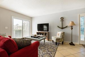 a living room with a red couch and a tv at TIDES BEACH PARADISE best served patch of beach in Jacksonville Beach