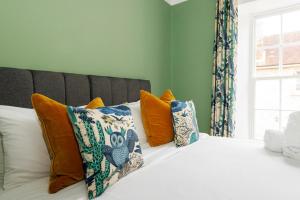 a bed with orange and blue pillows and a window at St Richard's Apartment in Chichester