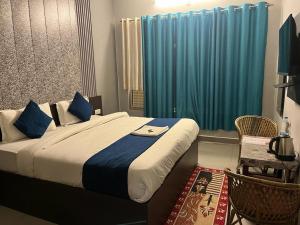a bedroom with a large bed with blue curtains at Hotel devoy inn by namastexplorer in Rishīkesh