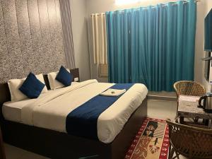 a bedroom with a large bed with blue curtains at Hotel devoy inn by namastexplorer in Rishīkesh