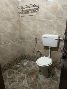 a bathroom with a toilet in a tiled room at Hotel devoy inn by namastexplorer in Rishīkesh