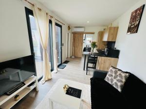 a living room with a black couch and a kitchen at Villa Louméa - Le Loft avec jacuzzi in Friesenheim