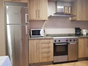 a kitchen with a stainless steel refrigerator and a microwave at VibesMuxía -Casa Rural Corredoira in Muxia