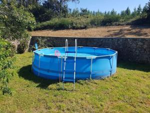 a blue boat sitting in the grass next to a wall at VibesMuxía -Casa Rural Corredoira in Muxia