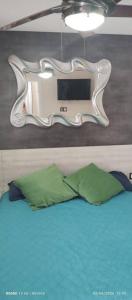 um espelho por cima de uma cama com uma almofada verde em Zoraida del MaryReviva Canarias em El Pris