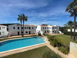 une villa avec une piscine et des palmiers dans l'établissement ALBATROS 48 by SOM Menorca, à Son Parc