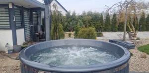 une grande baignoire d'eau devant une maison dans l'établissement Tęczowy Domek - Balia z hydromasażem, à Darłowo