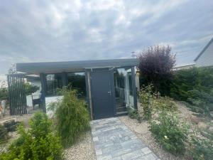 une maison avec une porte bleue dans un jardin dans l'établissement Tęczowy Domek - Balia z hydromasażem, à Darłowo