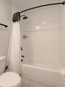 a white bathroom with a toilet and a bath tub at Fun Cozy Apts - 1 25 Mile Walk to TIAA Bnk Fld in Jacksonville