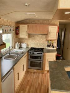 a small kitchen with a stove and a sink at Caravan hire Winthorpe Skegness in Skegness