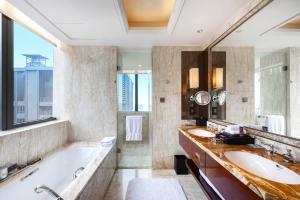 een badkamer met 2 wastafels, een bad en een groot raam bij The Ritz-Carlton, Chengdu in Chengdu