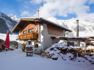 a house in the snow with mountains in the background at Cosy holiday home in L ngenfeld in Längenfeld